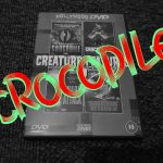 A black and white image of a DVD case with the word "CROCODILE" in green and red writing stamped across it